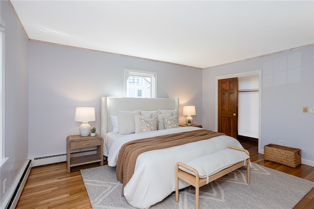 bedroom featuring hardwood / wood-style floors, ornamental molding, baseboard heating, and a closet