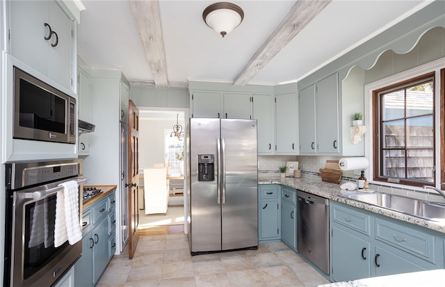 kitchen with blue cabinets, sink, decorative backsplash, appliances with stainless steel finishes, and beam ceiling