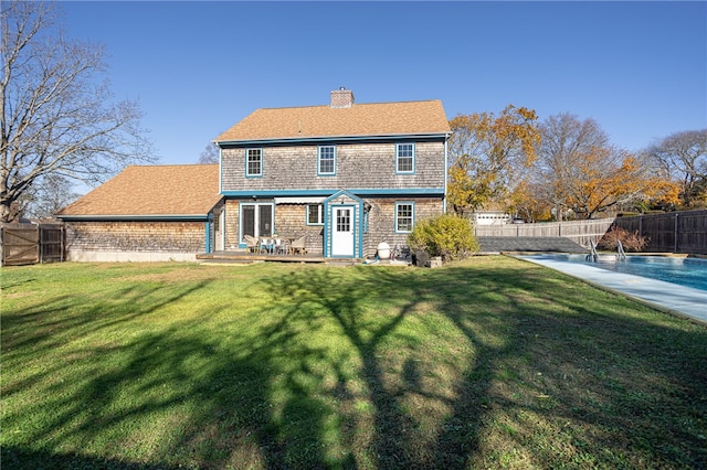 rear view of property featuring a yard and a pool side deck