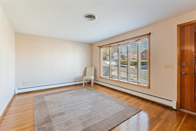 unfurnished room featuring a baseboard heating unit and light wood-type flooring