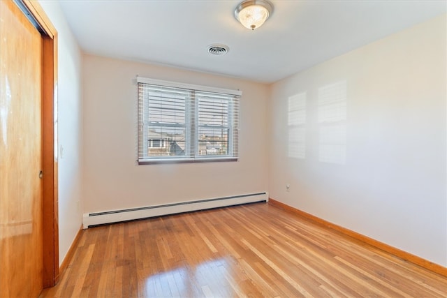 unfurnished bedroom with a closet, light hardwood / wood-style floors, and a baseboard heating unit