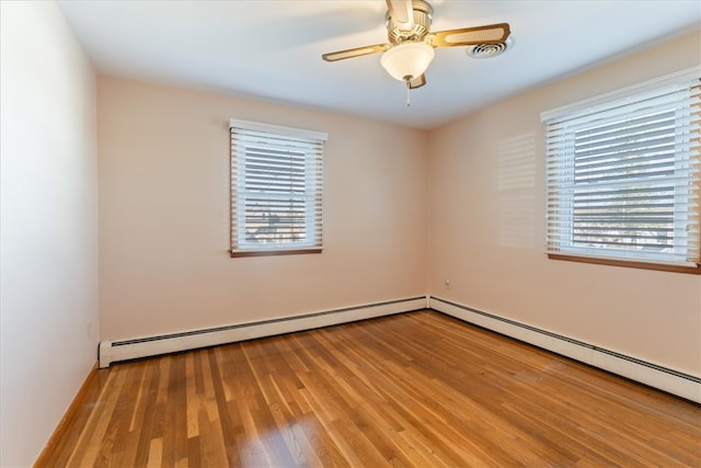 spare room featuring light wood-type flooring, plenty of natural light, a baseboard heating unit, and ceiling fan