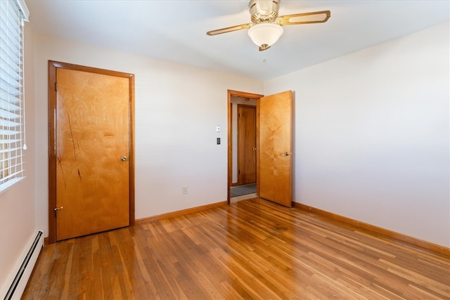 empty room featuring hardwood / wood-style floors, ceiling fan, and baseboard heating