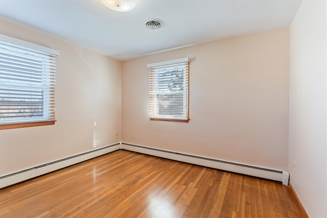 empty room featuring wood-type flooring and a baseboard heating unit