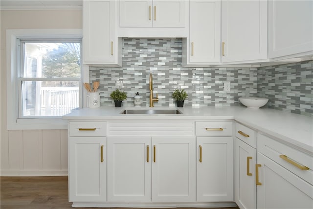 kitchen with white cabinets, backsplash, ornamental molding, and sink