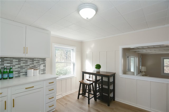 kitchen featuring backsplash, crown molding, light hardwood / wood-style flooring, and white cabinets