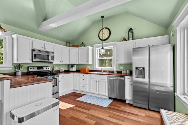 kitchen featuring appliances with stainless steel finishes, sink, decorative light fixtures, light hardwood / wood-style flooring, and white cabinetry