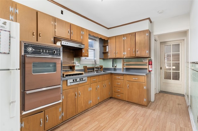 kitchen featuring white fridge, ventilation hood, sink, black oven, and light hardwood / wood-style floors