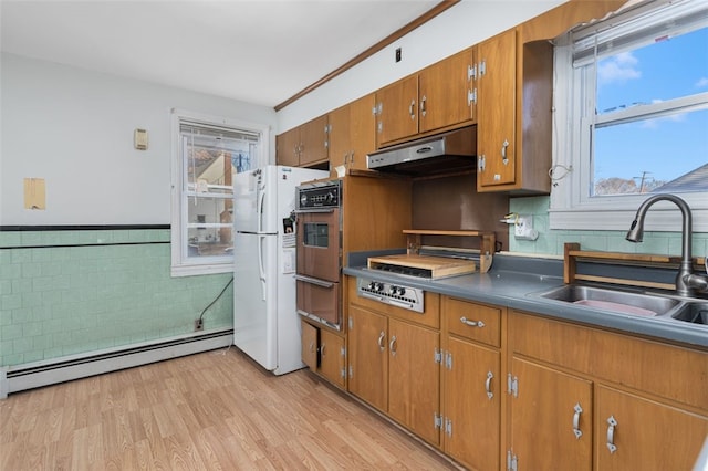 kitchen with extractor fan, baseboard heating, sink, white fridge, and oven