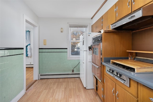 kitchen featuring white fridge, a baseboard radiator, tile walls, and light hardwood / wood-style floors