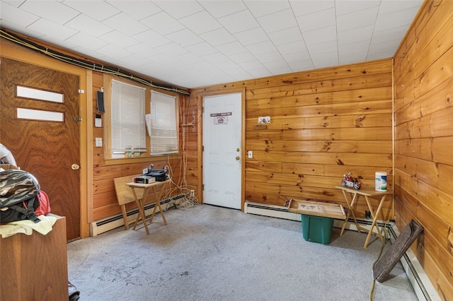 misc room featuring carpet flooring, wooden walls, and a baseboard radiator