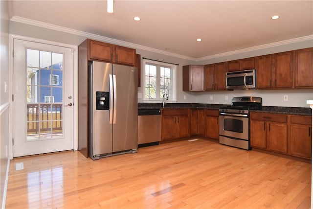 kitchen with a healthy amount of sunlight, light hardwood / wood-style floors, ornamental molding, and appliances with stainless steel finishes