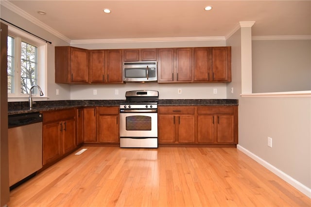 kitchen with appliances with stainless steel finishes, light hardwood / wood-style floors, crown molding, and sink