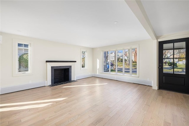 unfurnished living room featuring light hardwood / wood-style flooring and a brick fireplace