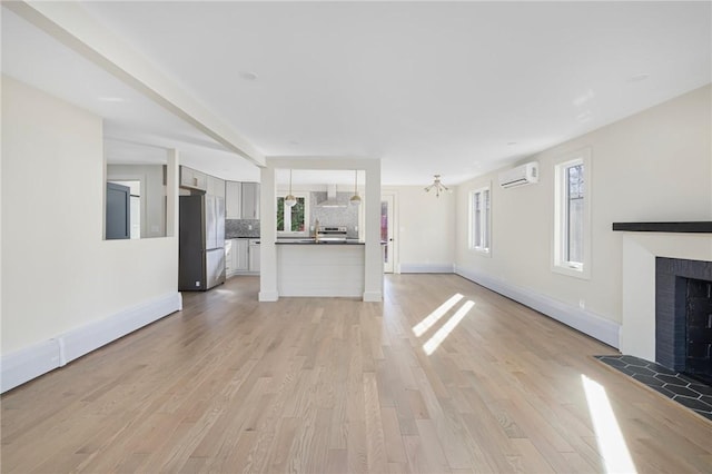 unfurnished living room featuring light hardwood / wood-style flooring and an AC wall unit