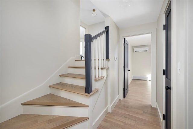 staircase with a wall unit AC and wood-type flooring