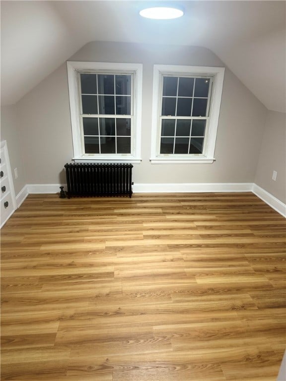 bonus room with light hardwood / wood-style flooring, radiator, and lofted ceiling