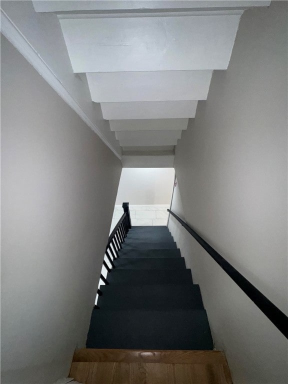 stairway featuring beam ceiling and crown molding