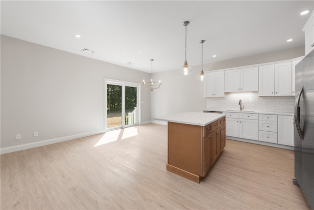 kitchen with decorative light fixtures, a center island, light wood-type flooring, and white cabinetry