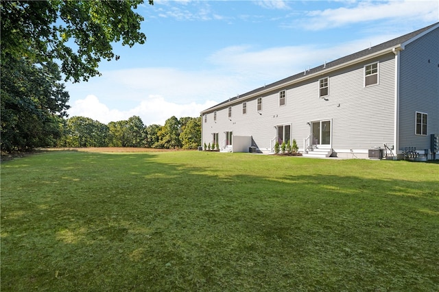 back of property featuring a yard and central AC