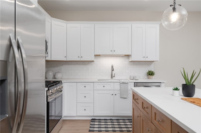 kitchen with white cabinets, sink, stainless steel appliances, and hanging light fixtures