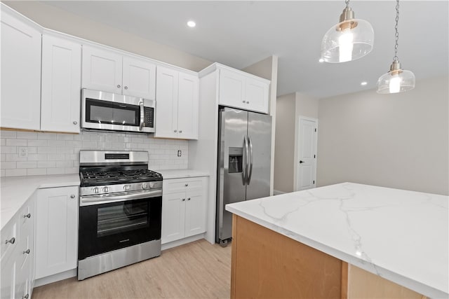 kitchen with pendant lighting, light stone counters, white cabinetry, and stainless steel appliances