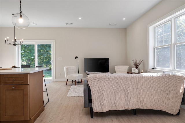 living room with a chandelier, light hardwood / wood-style flooring, and a wealth of natural light