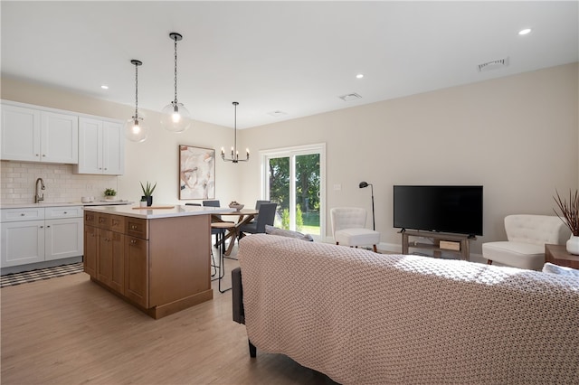 living room featuring light wood-type flooring, an inviting chandelier, and sink