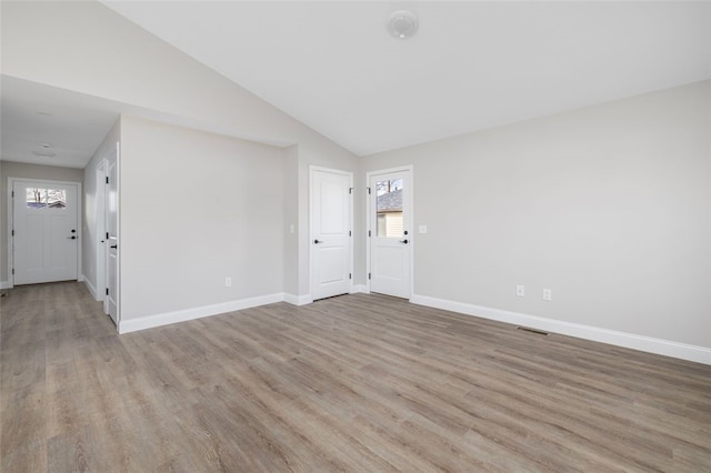 empty room featuring light hardwood / wood-style floors and vaulted ceiling