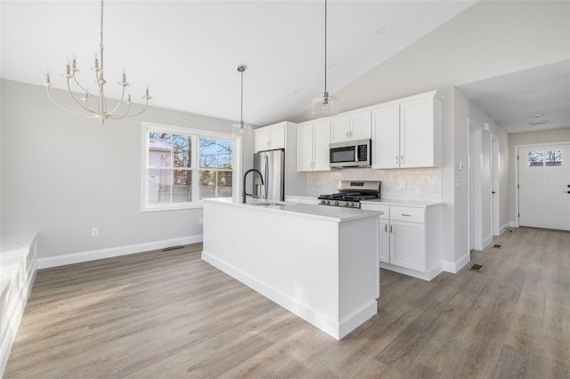 kitchen featuring white cabinets, stainless steel appliances, and decorative light fixtures