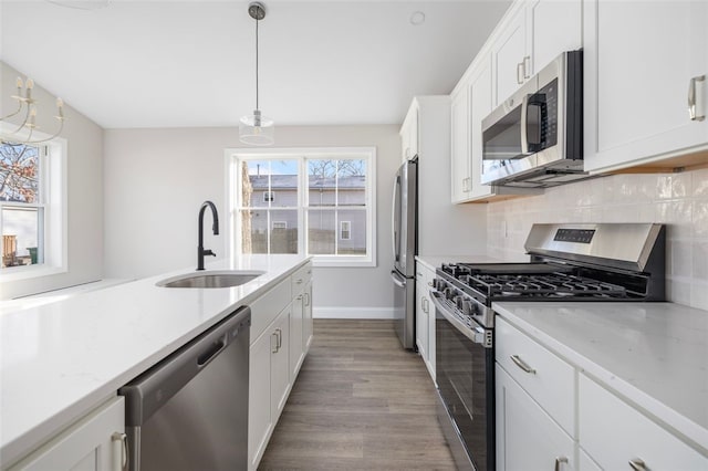 kitchen featuring white cabinets, sink, light hardwood / wood-style flooring, decorative light fixtures, and stainless steel appliances