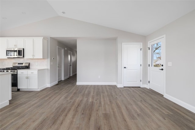 kitchen with appliances with stainless steel finishes, light hardwood / wood-style floors, white cabinetry, and lofted ceiling