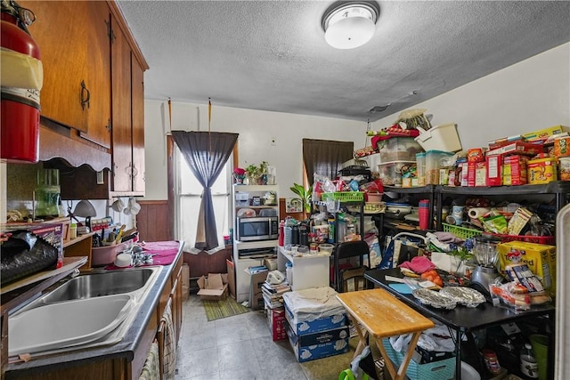 kitchen with a textured ceiling, wood walls, and sink