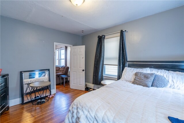 bedroom with wood-type flooring and multiple windows