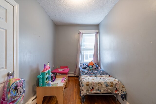 bedroom with hardwood / wood-style flooring, a textured ceiling, and a baseboard radiator