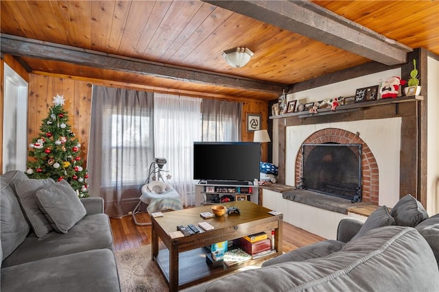 living room featuring a brick fireplace, beam ceiling, wooden ceiling, hardwood / wood-style floors, and wood walls