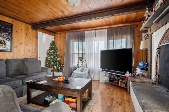 living room with beam ceiling, light hardwood / wood-style flooring, wood ceiling, and wood walls