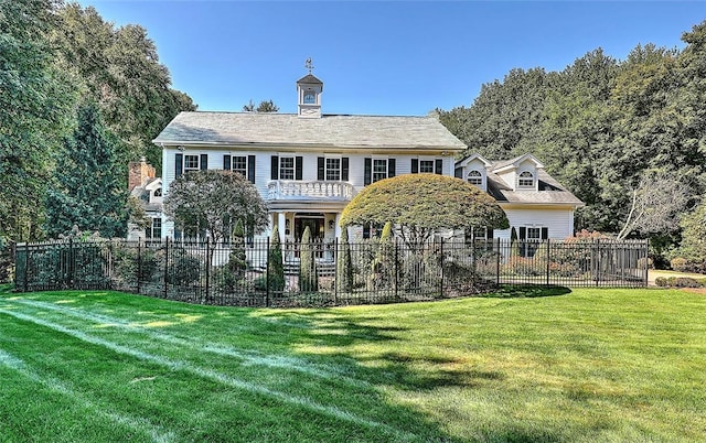 rear view of house featuring a balcony and a lawn