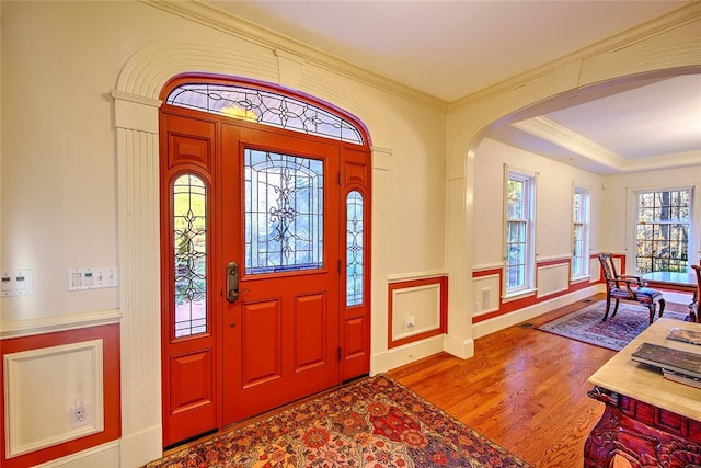 foyer entrance with light wood-type flooring, crown molding, and a wealth of natural light