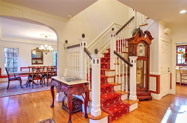 stairs with hardwood / wood-style floors, a chandelier, and ornamental molding