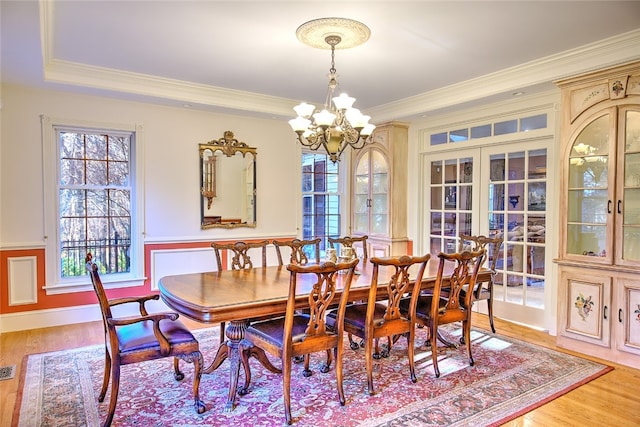 dining room with hardwood / wood-style floors, an inviting chandelier, ornamental molding, and french doors