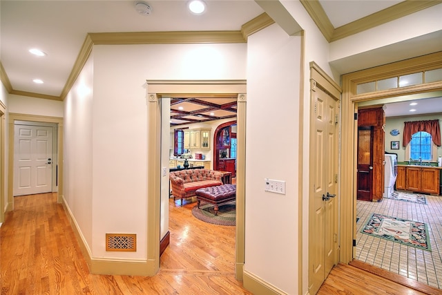 hallway featuring light hardwood / wood-style flooring, coffered ceiling, and ornamental molding