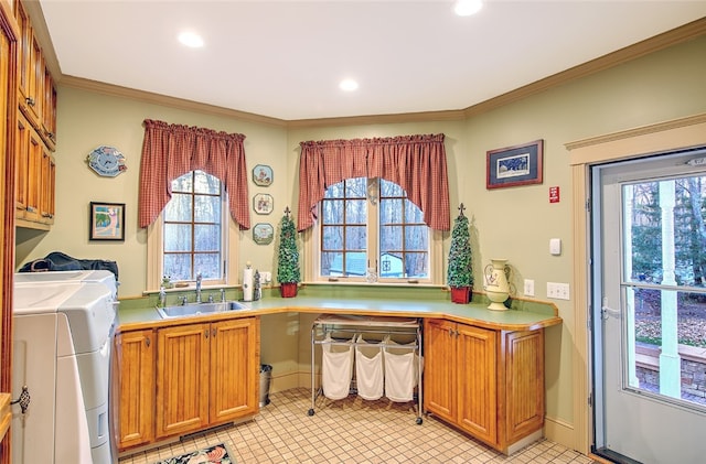 clothes washing area featuring crown molding, cabinets, sink, and a wealth of natural light