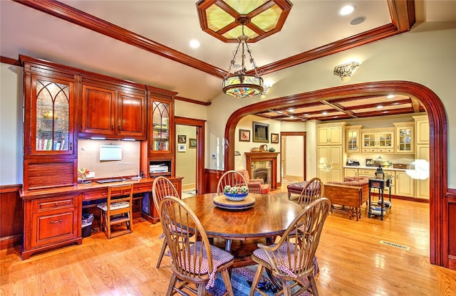 dining space featuring light hardwood / wood-style floors, ornamental molding, and coffered ceiling