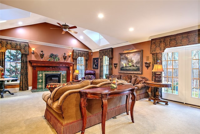 carpeted living room with a fireplace, lofted ceiling with skylight, ceiling fan, and crown molding