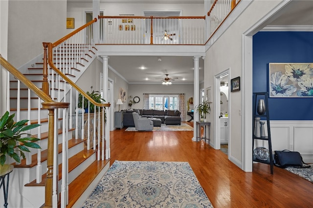 entryway with a high ceiling, hardwood / wood-style flooring, ornate columns, and crown molding