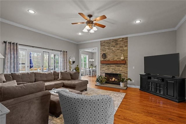 living room with wood-type flooring, ornamental molding, a fireplace, and ceiling fan