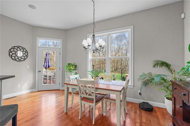 dining space with light hardwood / wood-style floors and a chandelier