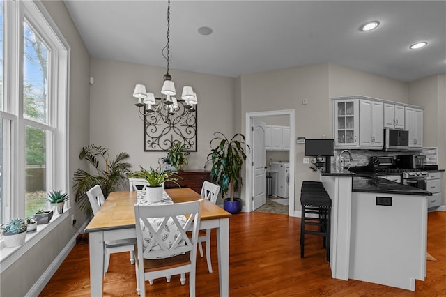 dining space with wood-type flooring, sink, and an inviting chandelier