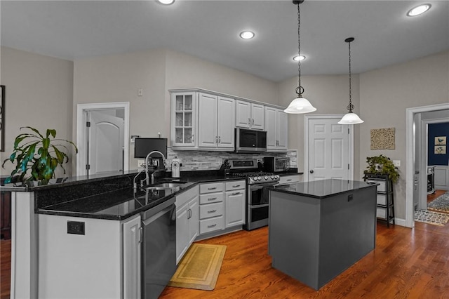 kitchen featuring sink, a center island, hanging light fixtures, stainless steel appliances, and decorative backsplash